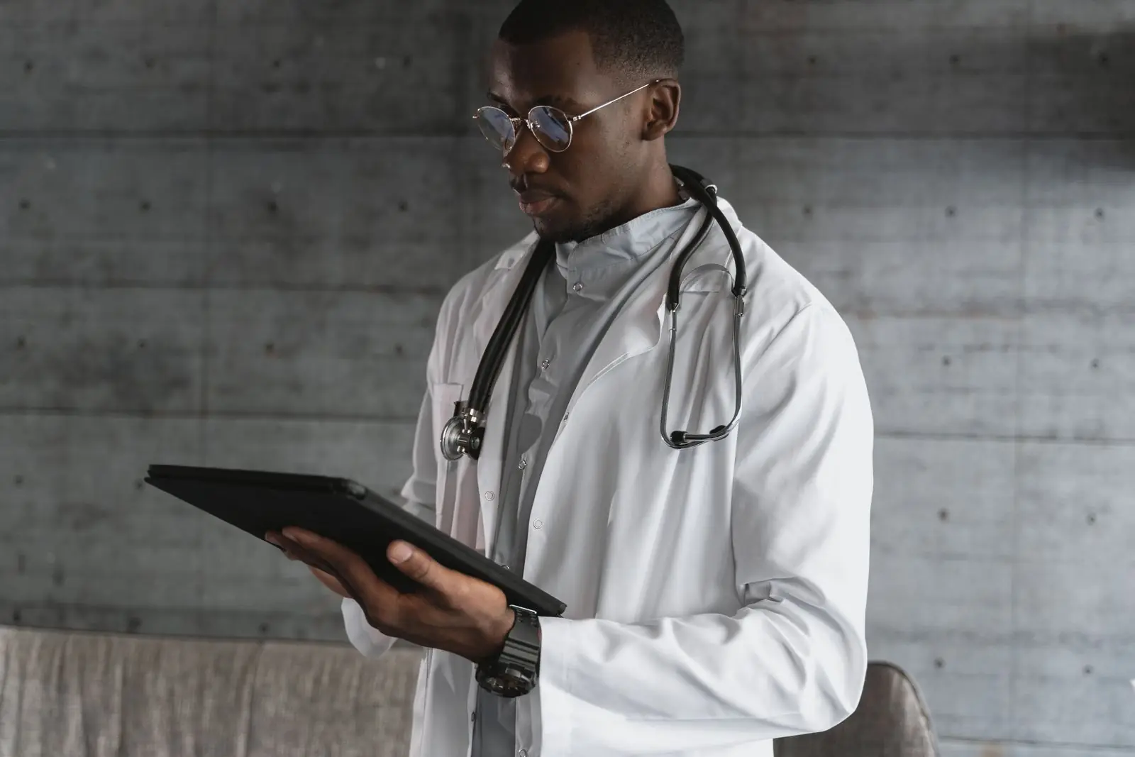 Physician in a white coat reviewing a tablet