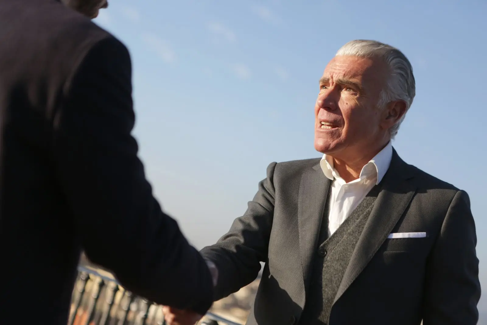 Senior professional shaking hands with a partner outdoors