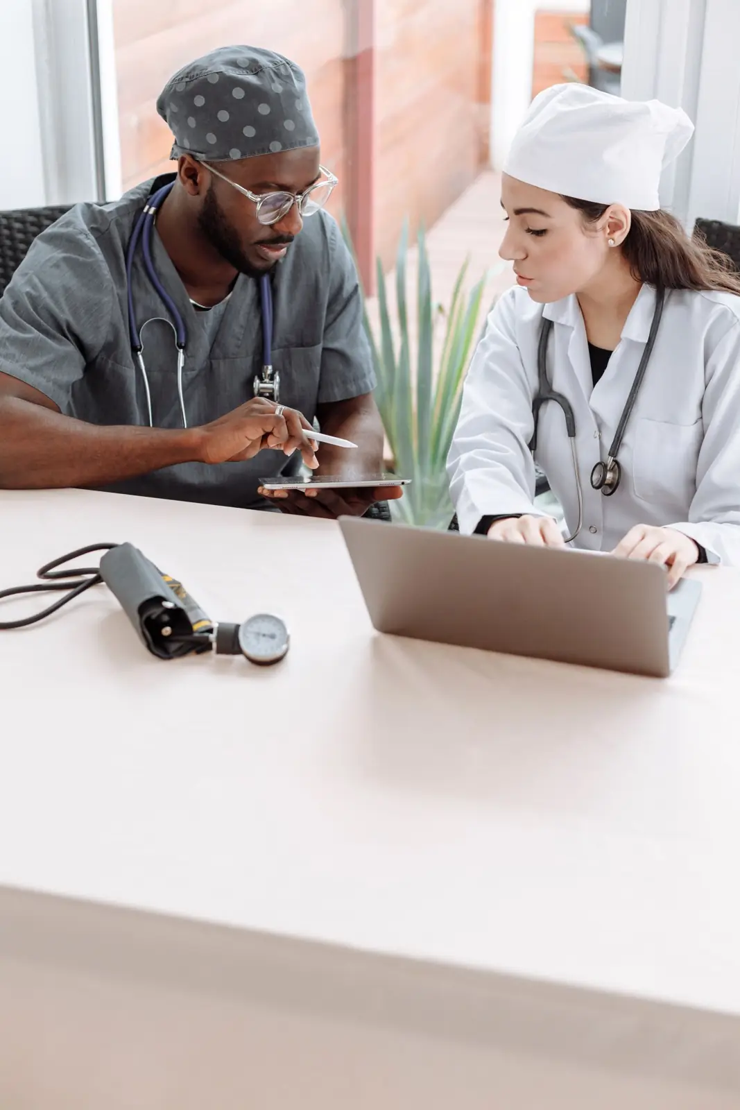 Two physicians reviewing information on a tablet and laptop