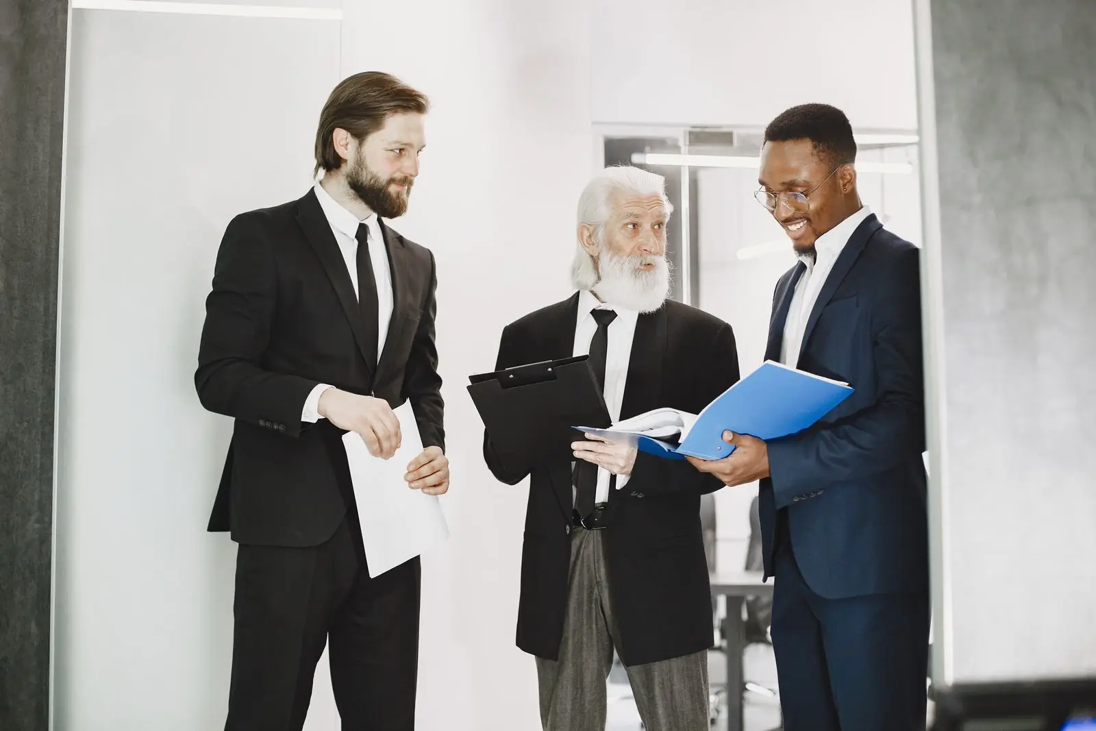 Three businessmen in suits reviewing deal documents